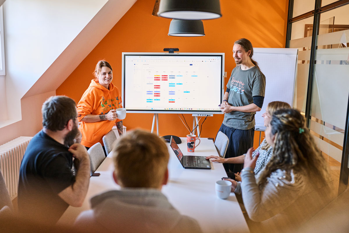 Das soft-park-Team bespricht ein Projekt im Meetingraum vor einem großen Bildschirm mit einem bunten Planungsdiagramm